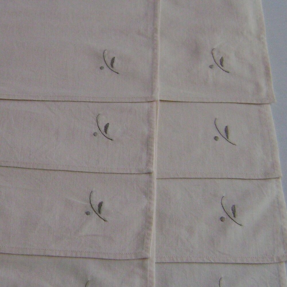 Eight cotton or cottonblend offwhite napkins with embroidery at corner
